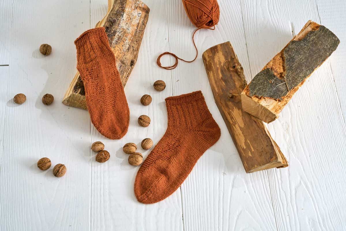 braune Socken liegend neben Holzscheiten