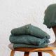 jacken und pullover aus merinowolle in unterschiedlichen gruentoenen auf holzstuhl
