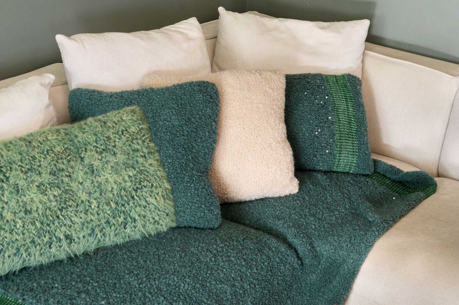 plaids und kissen aus wuscheliger wolle in beige und gruentoenen